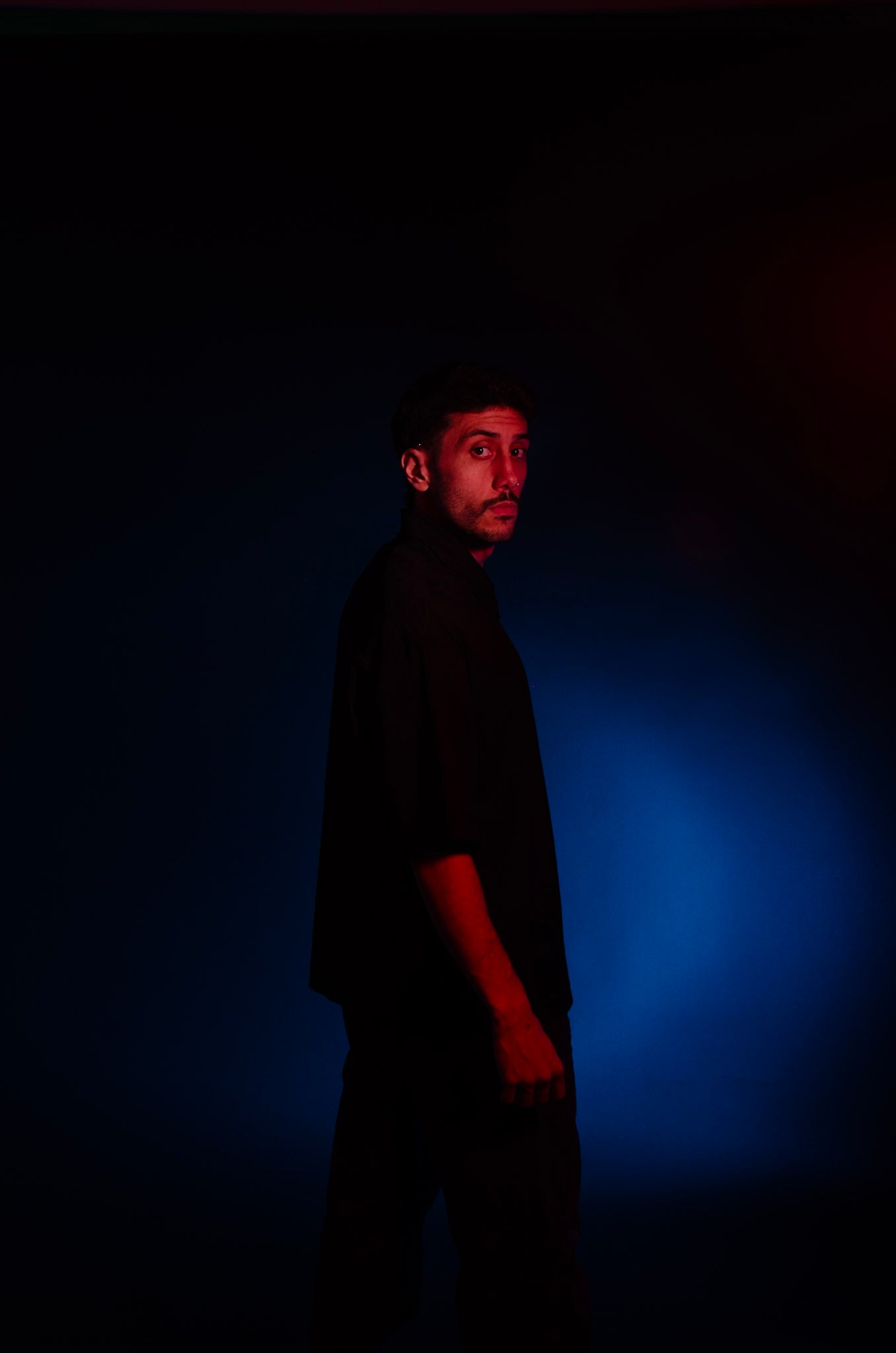 DJ standing in a dark room with blue light casting shadows