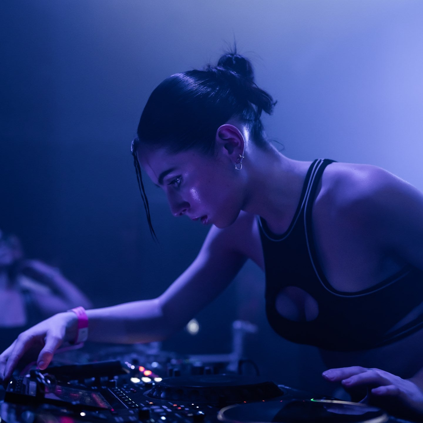 DJ operating turntables in a dark setting with blue lighting